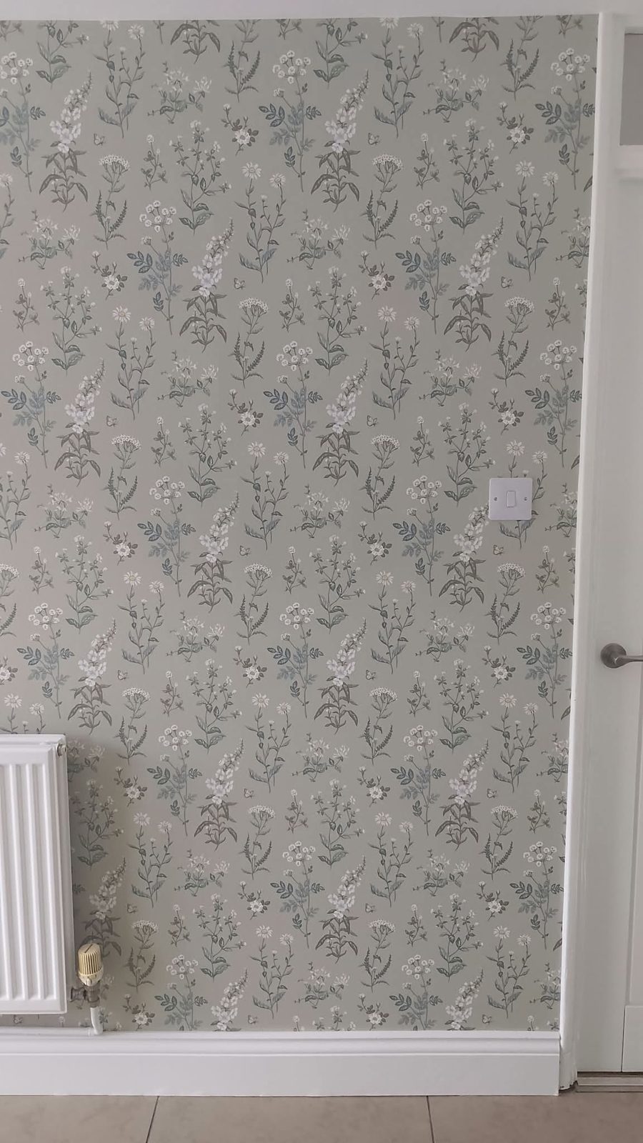 Sage floral wallpaper hung beside a doorway