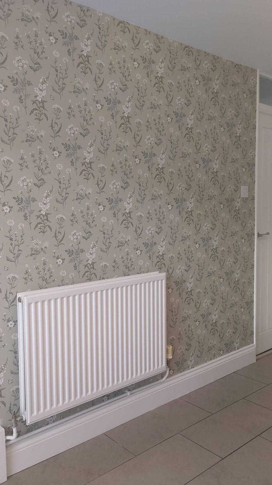 Feature wall in a sage floral wallpaper above a white radiator