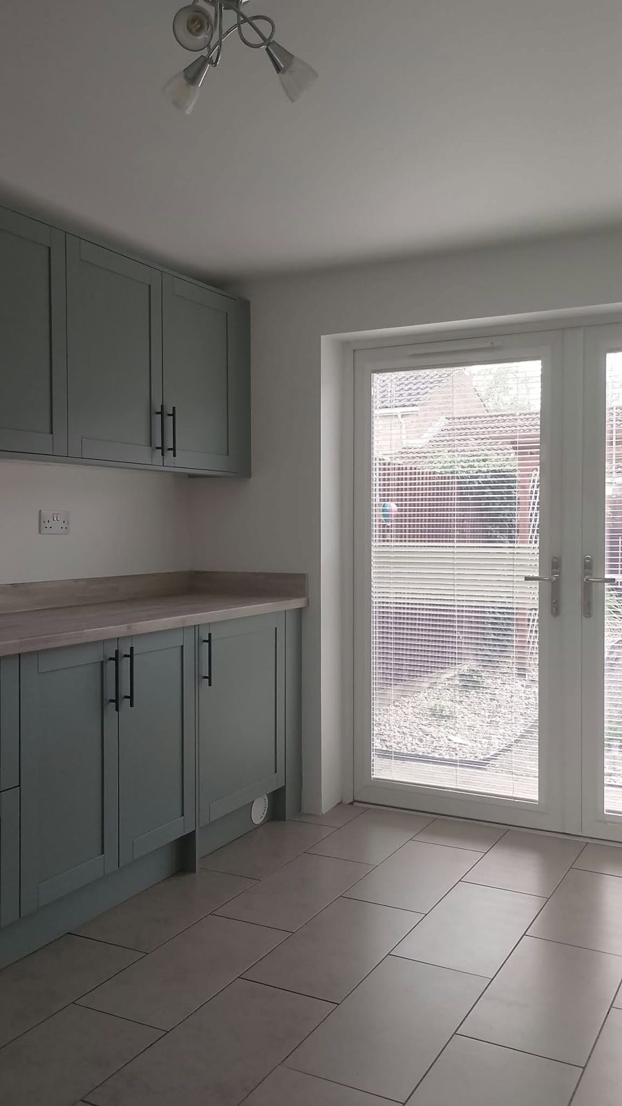 Kitchen units leading to glazed doors, with white walls