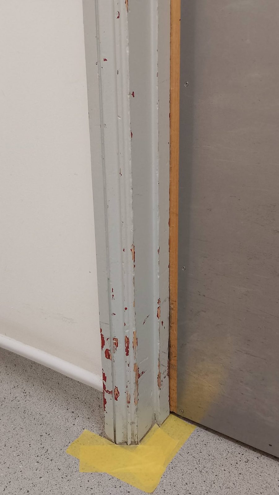 A chipped and scuffed door frame in a surgery corridor before decorating