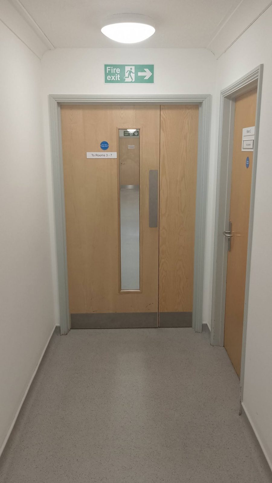 Surgery corridor with a fire exit sign over freshly painted door frames