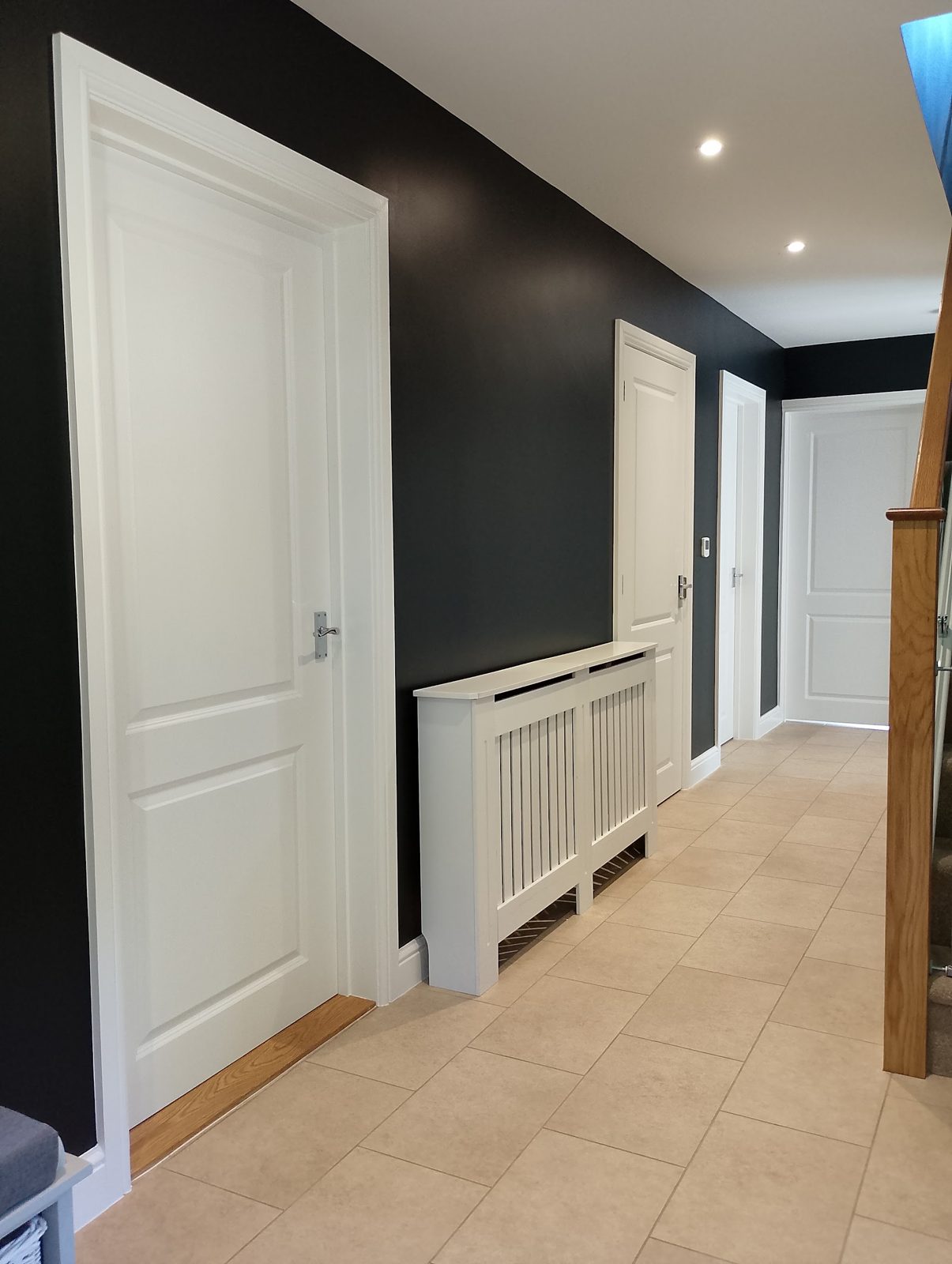 Hallway with charcoal walls, white doors and a white radiator cover