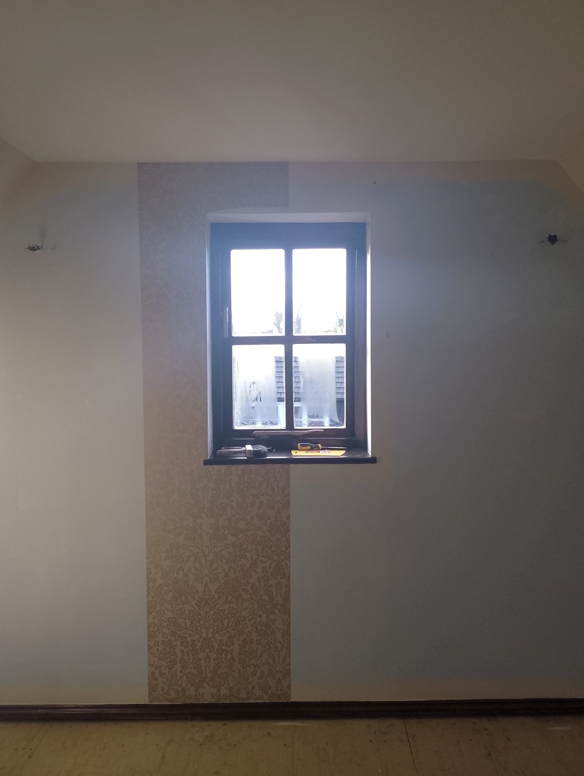 A room mid-way through papering, with the first length hung beside the window